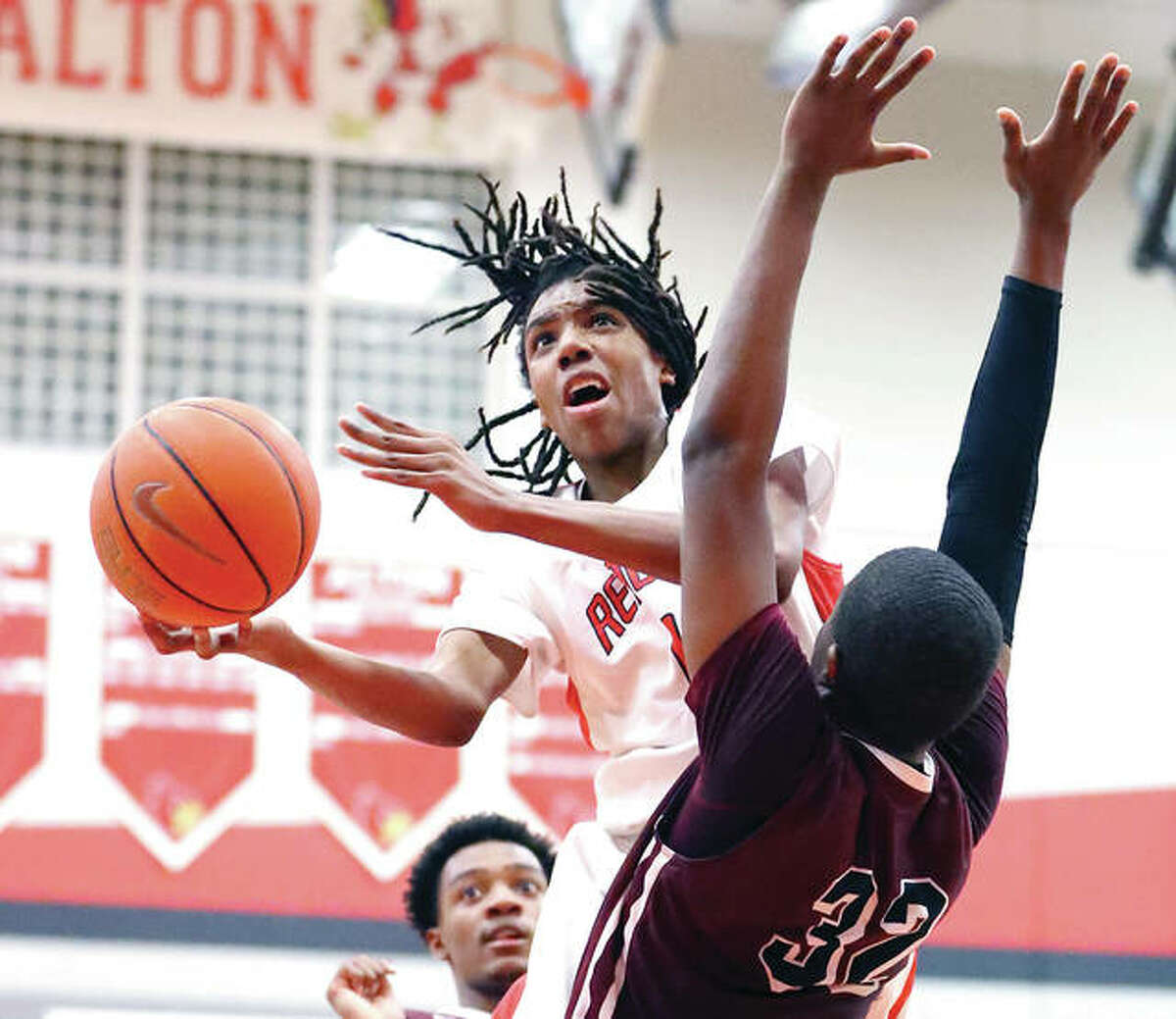Alton’s Donovan Clay and the Redbirds opened tourney play at Belleville East on Tuesday night with a loss to Champaign Central. He is shownshooting around Belleville West’s E.J. Liddell (right) during a SWC game Jan. 5 at Alton High.