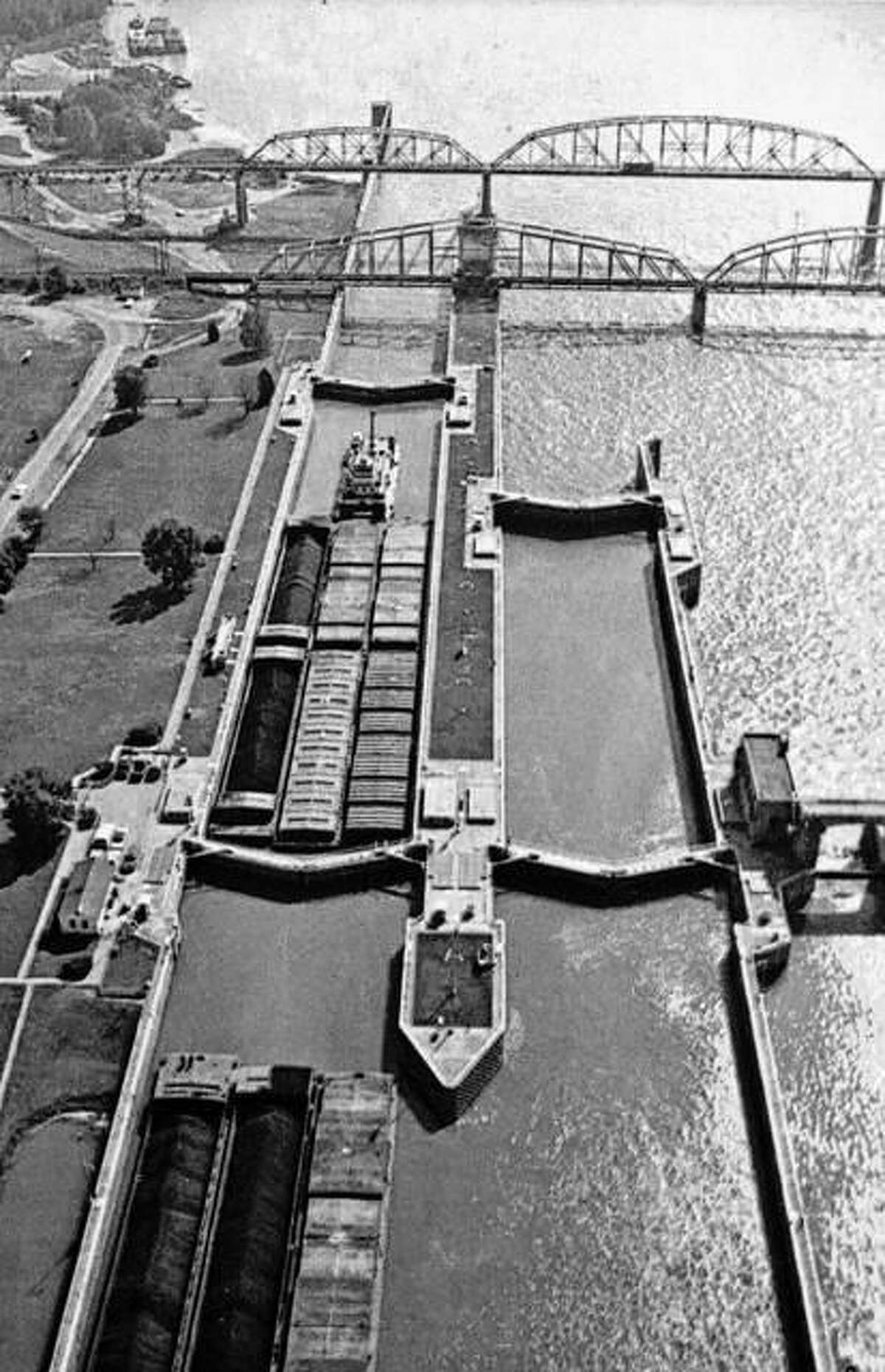 Barges pass through the Locks and Dam 26 at the Alton riverfront. The old Clark Bridge and railroad can also be seen.