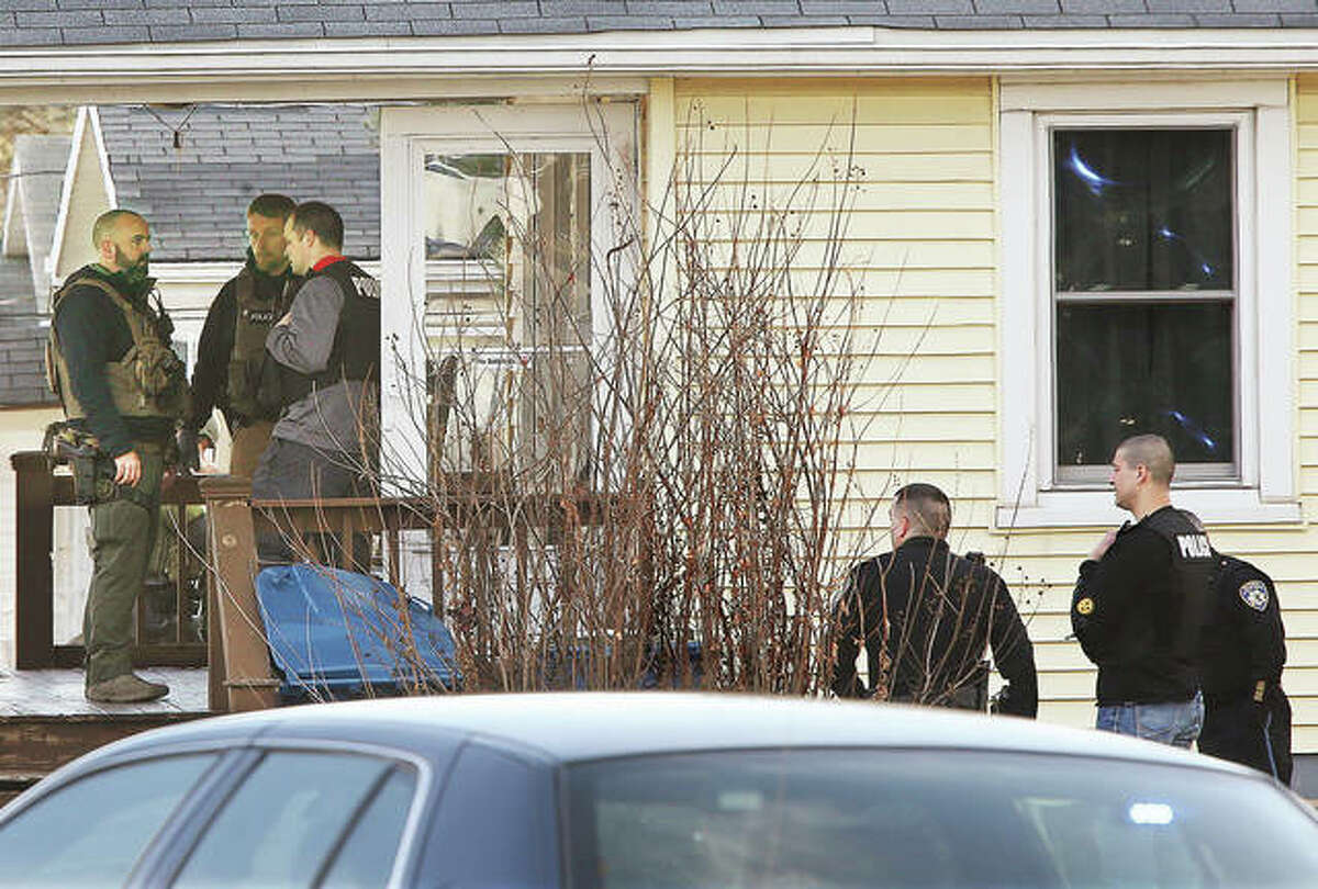 U.S. Marshals, left, and Alton police, right, stand outside a house Friday morning in the 3500 block of Omega Street, where a 42-year-old man was shot and killed during a warrant arrest. Madison County deputy coroners were called to the scene, and the street was being blocked by Alton police for a block in each direction. Alton police were apparently not initially involved in the operation until shots were reported being fired.