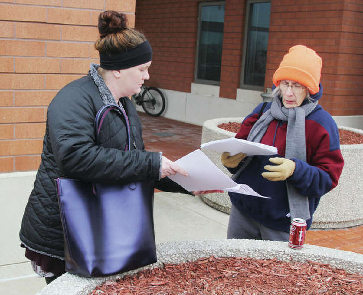 Brittany Pinnon , left, hands out forms to first-time volunteer Diane Martin for for the annual homeless count last year. The group met in front of the Donald E. Sandidge Alton Law Enforcement Center before fanning out. This year’s count is set for Monday.