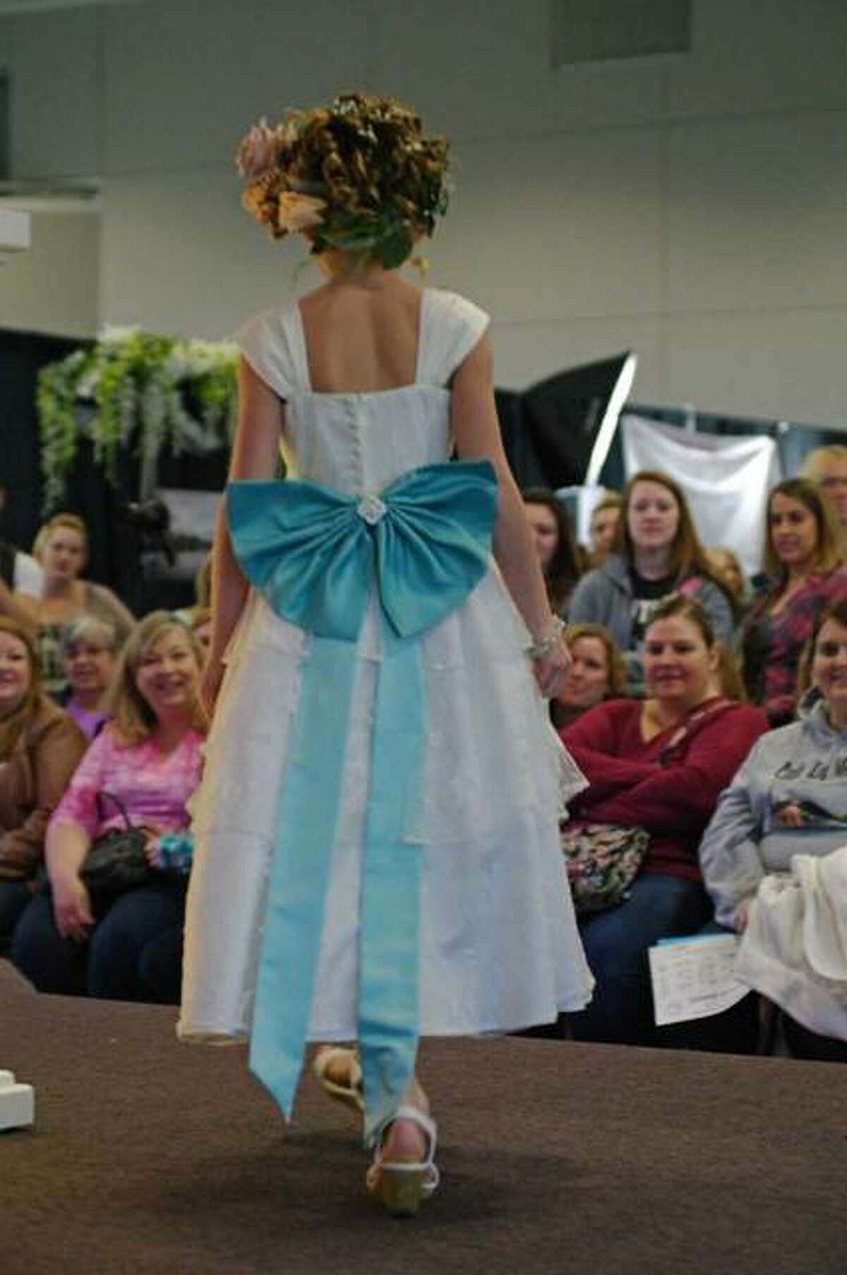 A flower girl dress being modeled at the bridal fashion show.