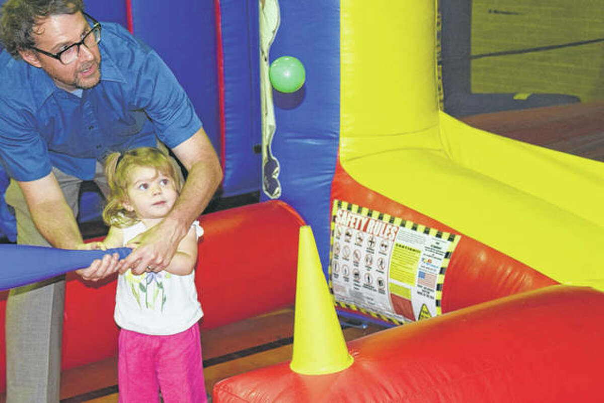 Marin Oldenburg, 2, tries to hit a floating ball with the help of her father, Chris Oldenburg of Jacksonville, during the Illinois College Osage Orange Festival in May 2016. The annual spring festival returns Friday to the IC campus.