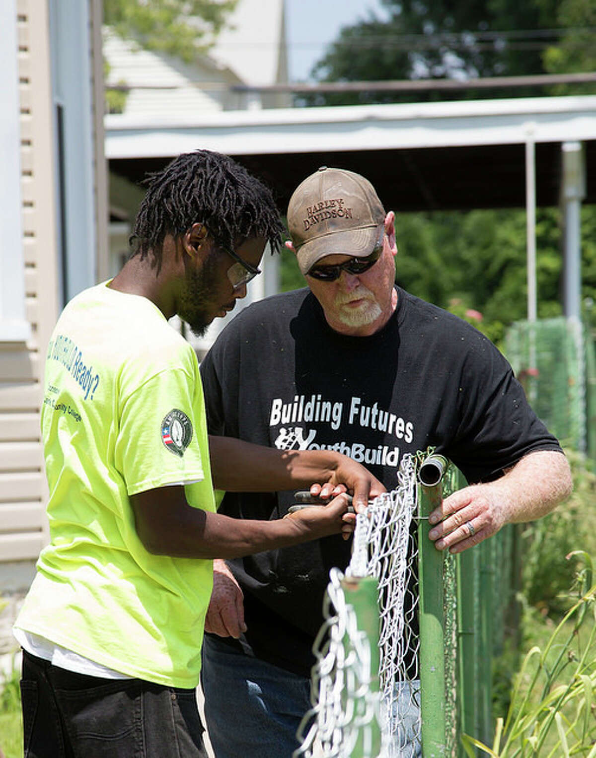 Andre Ewing works on the installation of a new fence with YouthBuild Construction Trainer Mitch Fletcher, as a part of the program’s 2016 Central Avenue Beautification project.