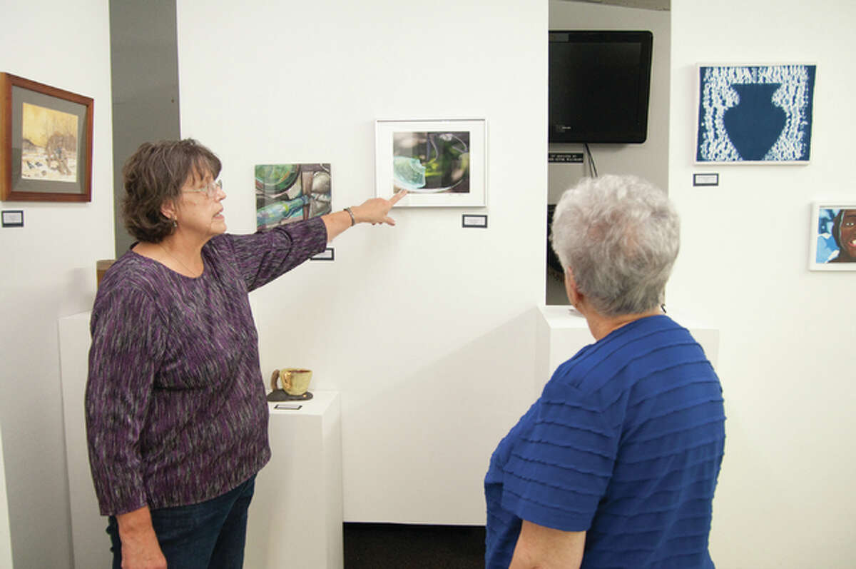 Wood River History Museum Art Show co-chairwoman Cheryl Maguire gives information to Janet Hunt about a photograph by Patrick Bellman. Bellman was one of 55 entrants with artwork at the fourth annual Wood River Museum Art Show Sunday.