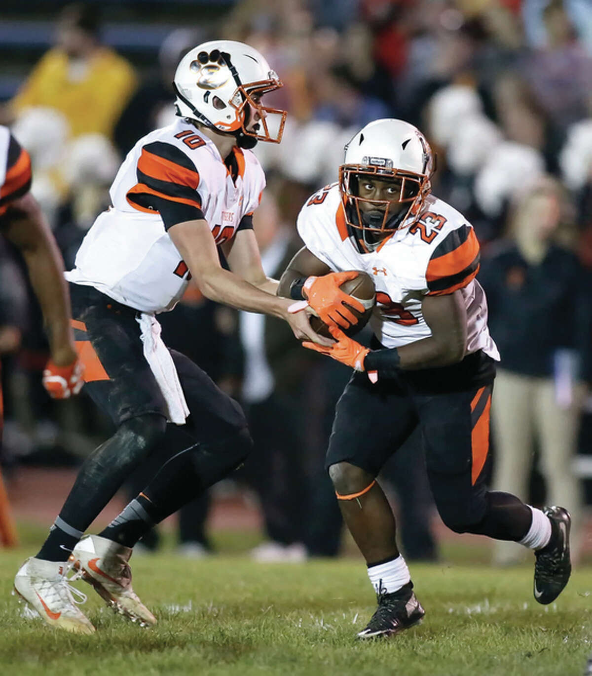 Edwardsville QB Brenden Dickmann (left) hands off to running back Dionte Rodgers on Friday night in Alton. Rodgers, a sophomore, finished with 211 rushing yards and three touchdowns from 16 carries.