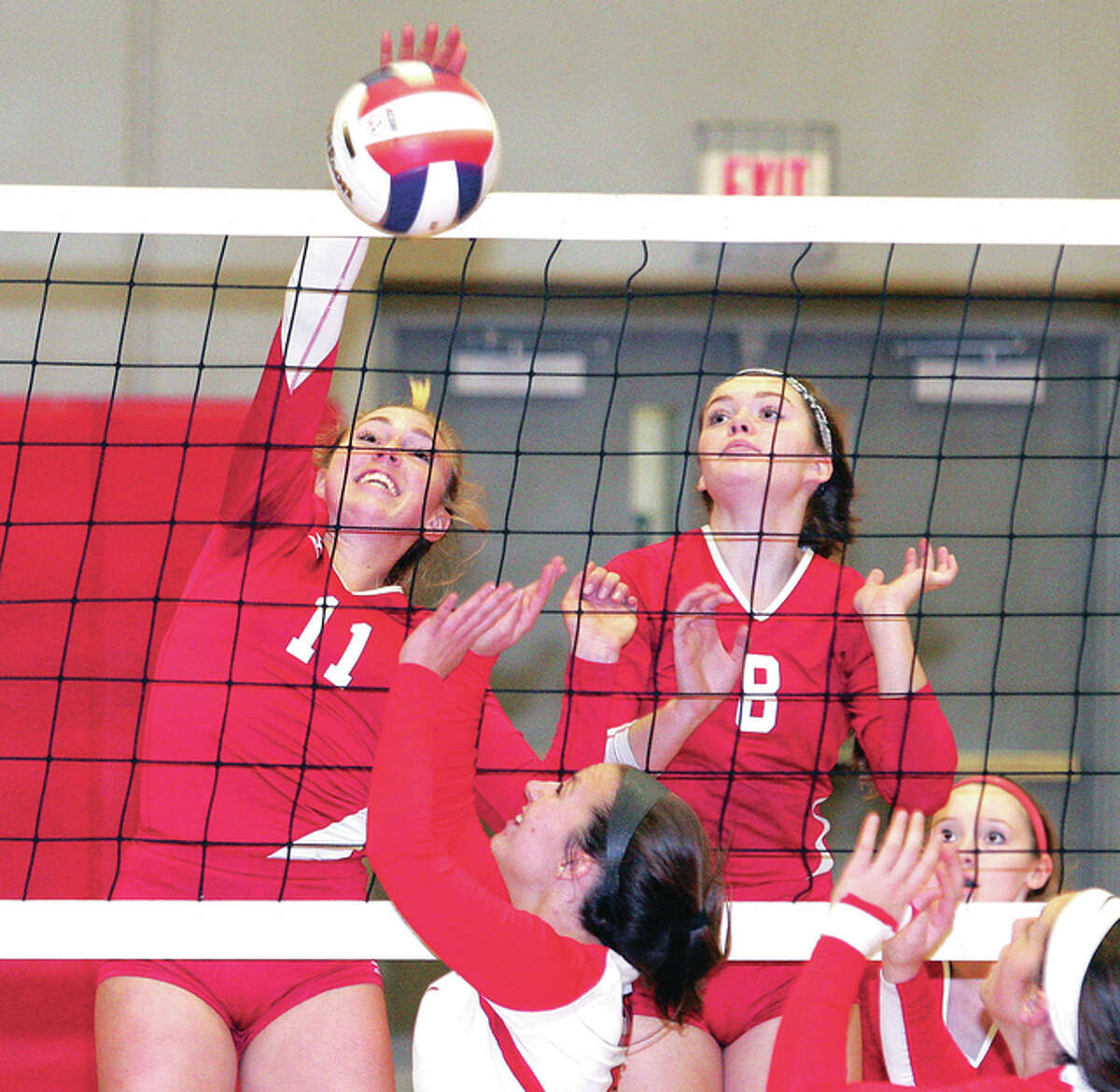 Alton senior Annie Evans, left, records a kill Monday night against Chatham Glenwood the Alton Class 4A Regional at Alton High in Godfrey. At right is Alton’s Saddie Brands.