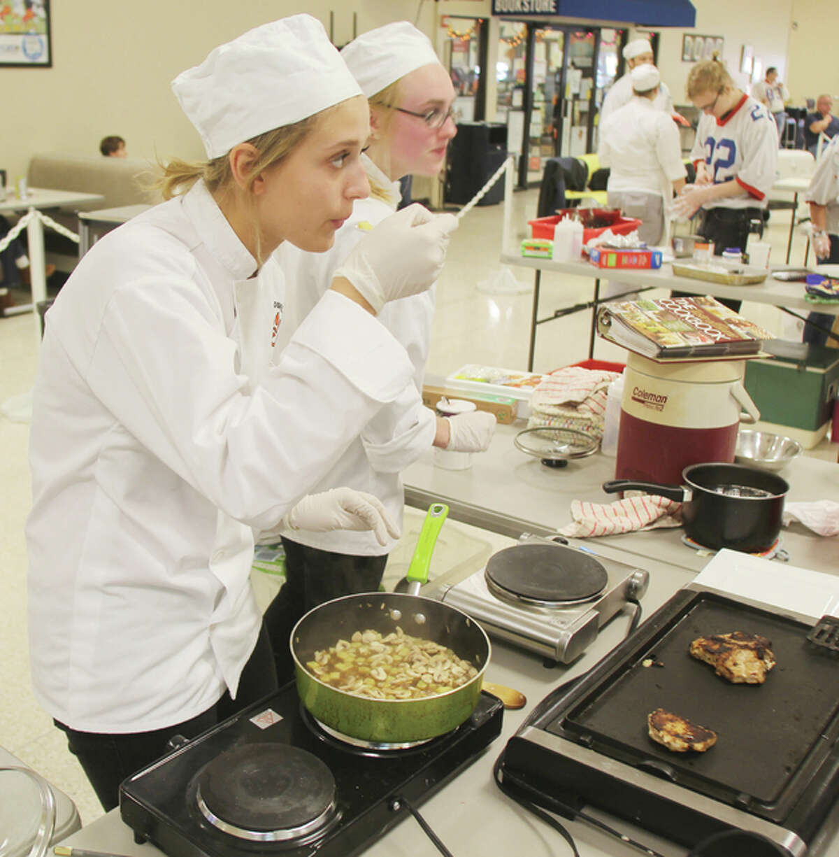 Edwardsville High School student Elizabeth Gaumer, left, tastes a dish while Laura Forsyth works on another dish during the Platinum Chef competition Wednesday at the Southwestern Illinois College Sam Wolf Granite City Campus. The competition, the first in Madison County, pitted culinary teams from six local high schools against each other.