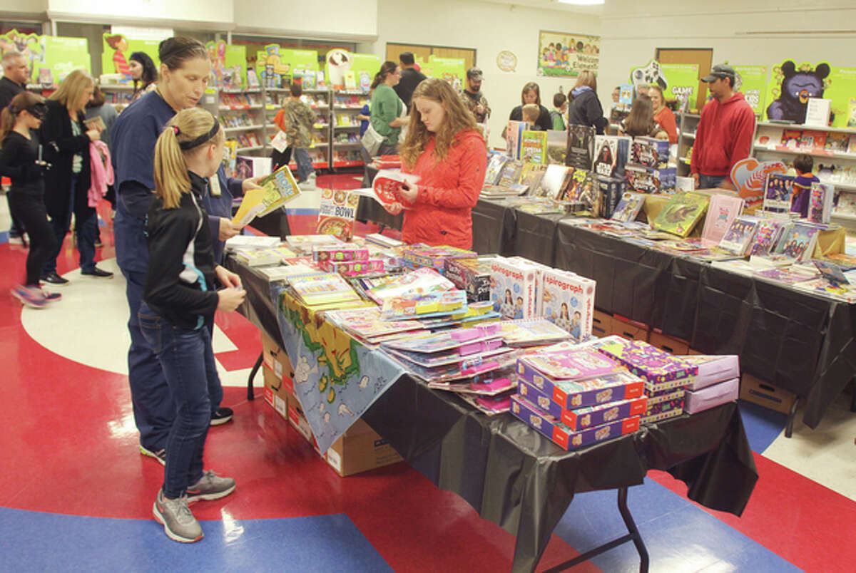 Children and adults look over books and other items at the East Elementary School family reading night and book fair Thursday. The event had a pirate theme.