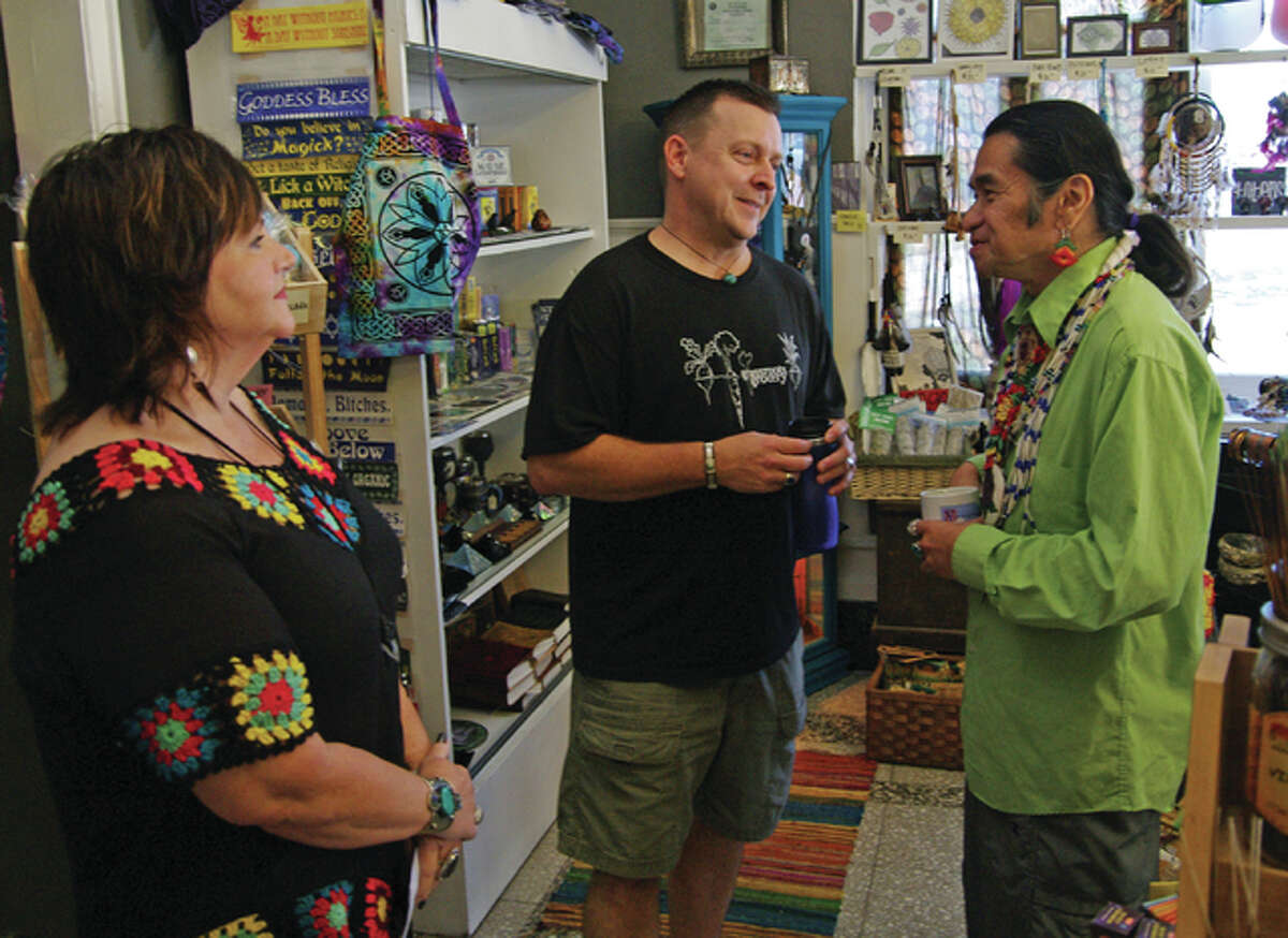 Donna and Dave Nunnally, owners of It’s Raining Zen, talk in their shop with Johnny Moses before a Native American program Moses gave in Mineral Springs Mall Sunday.