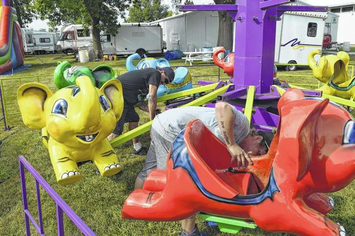 Carnival workers Joe Auman of LaSalle (left) and J.C. Womeldorff of Pekin inspect a children’s ride Monday at the Brown County Fairgrounds in Mount Sterling. The fair begins its six-day run today. Auman and Womeldorff work for Zeiler and Davis Amusements of Peoria.