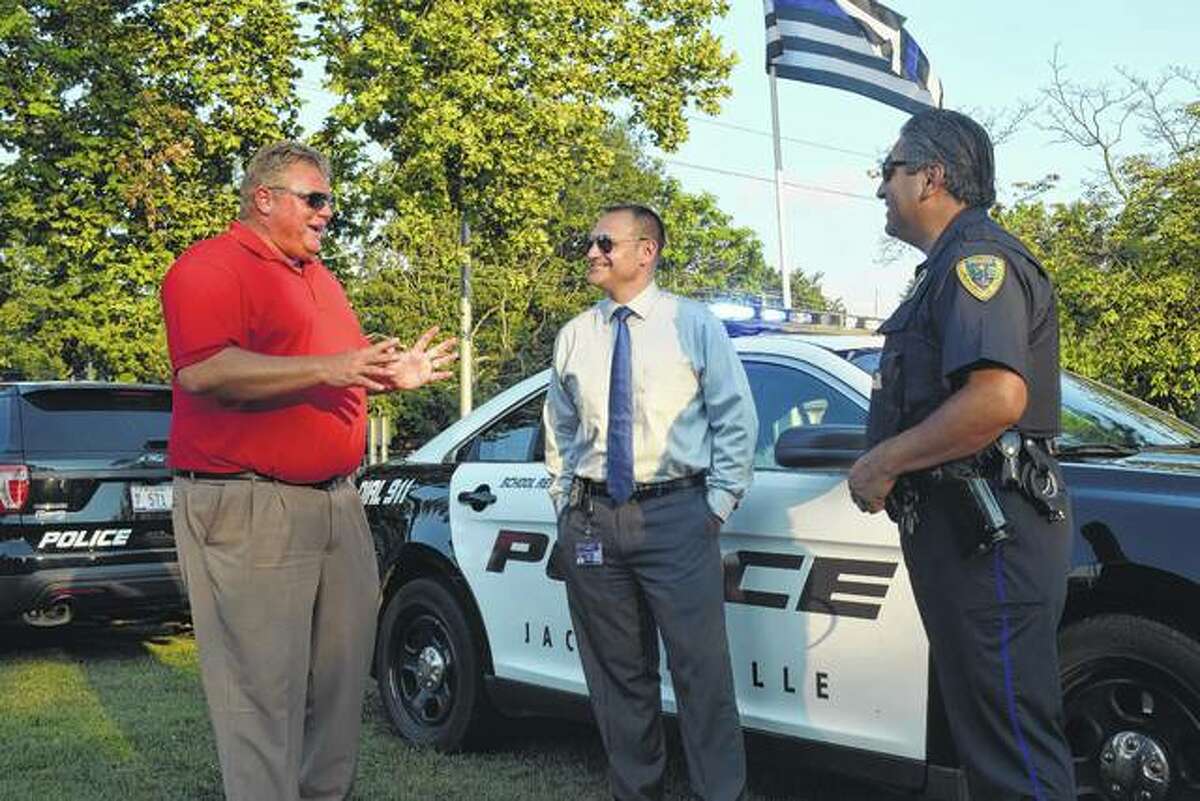 Jacksonville Mayor Andy Ezard (left) speaks with Jacksonville Police Chief Adam Mefford (center) and Tino Vasquez, a Jacksonville police patrolman, school resource officer and liaison with the Citizens Police Academy Alumni Association, Tuesday evening at the National Night Out event in Community Park.