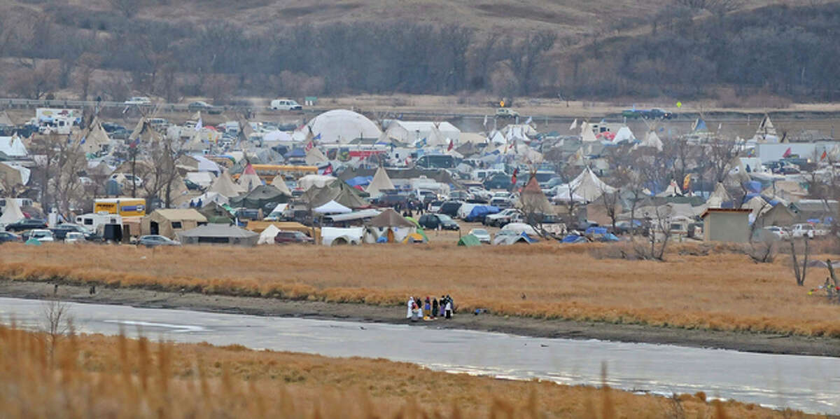 In this Nov. 24 photo, people stand on the edge of Cantapeta Creek near the growing Sacred Stones Overflow Protest Camp in Morton County, North Dakota. The leader of the Cheyenne River Sioux in South Dakota is calling for all opponents of the Dakota Access oil pipeline to boycott businesses in North Dakota’s capital city.