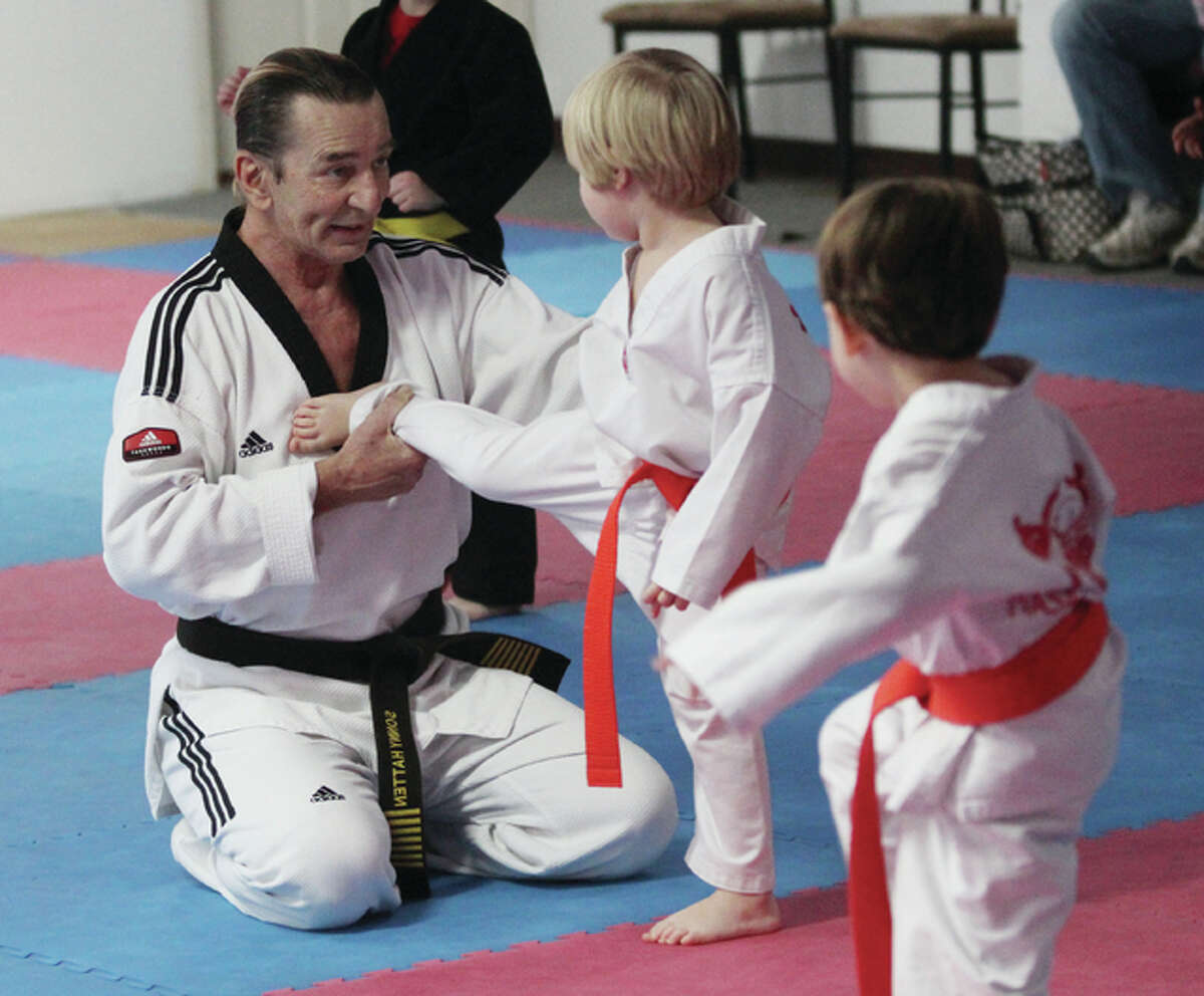 Sonny Hatten, of Piasa Martial Arts in Alton, shows orange belt Emmitt Hausman the proper way to kick during a class.