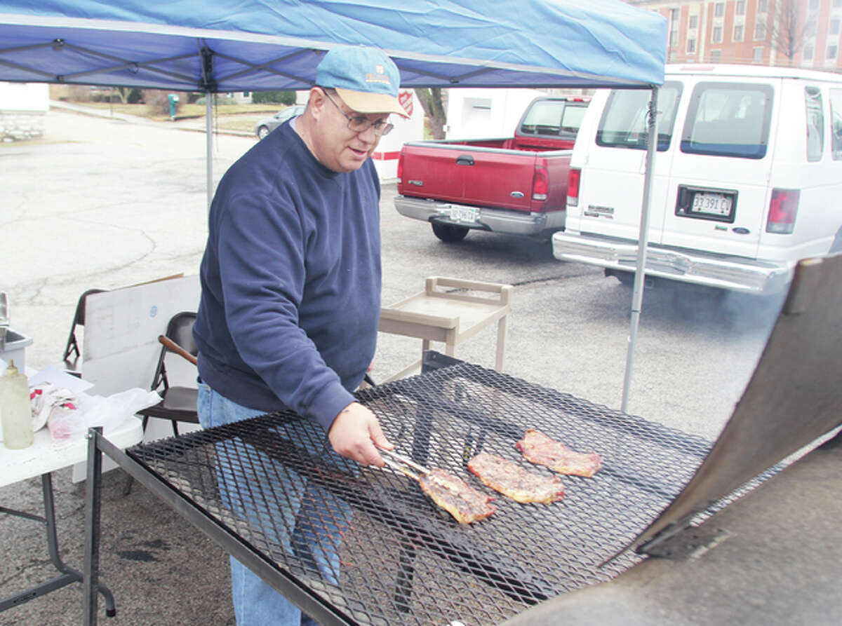 Greg Gelzinnis, the campaign coordinator for the Salvation Army’s Red Kettle Campaign, turns over pork steaks during the “Red Kettle Pork Steaktacular,” a final fundraising push for the campaign.