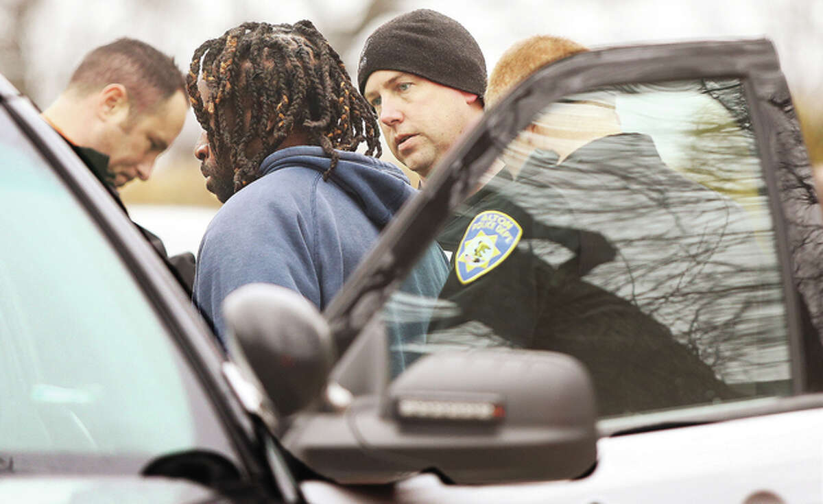 Alton Police detectives question one of the people removed from 2011 Mulberry in handcuffs Thursday before placing him in an Alton patrol car.