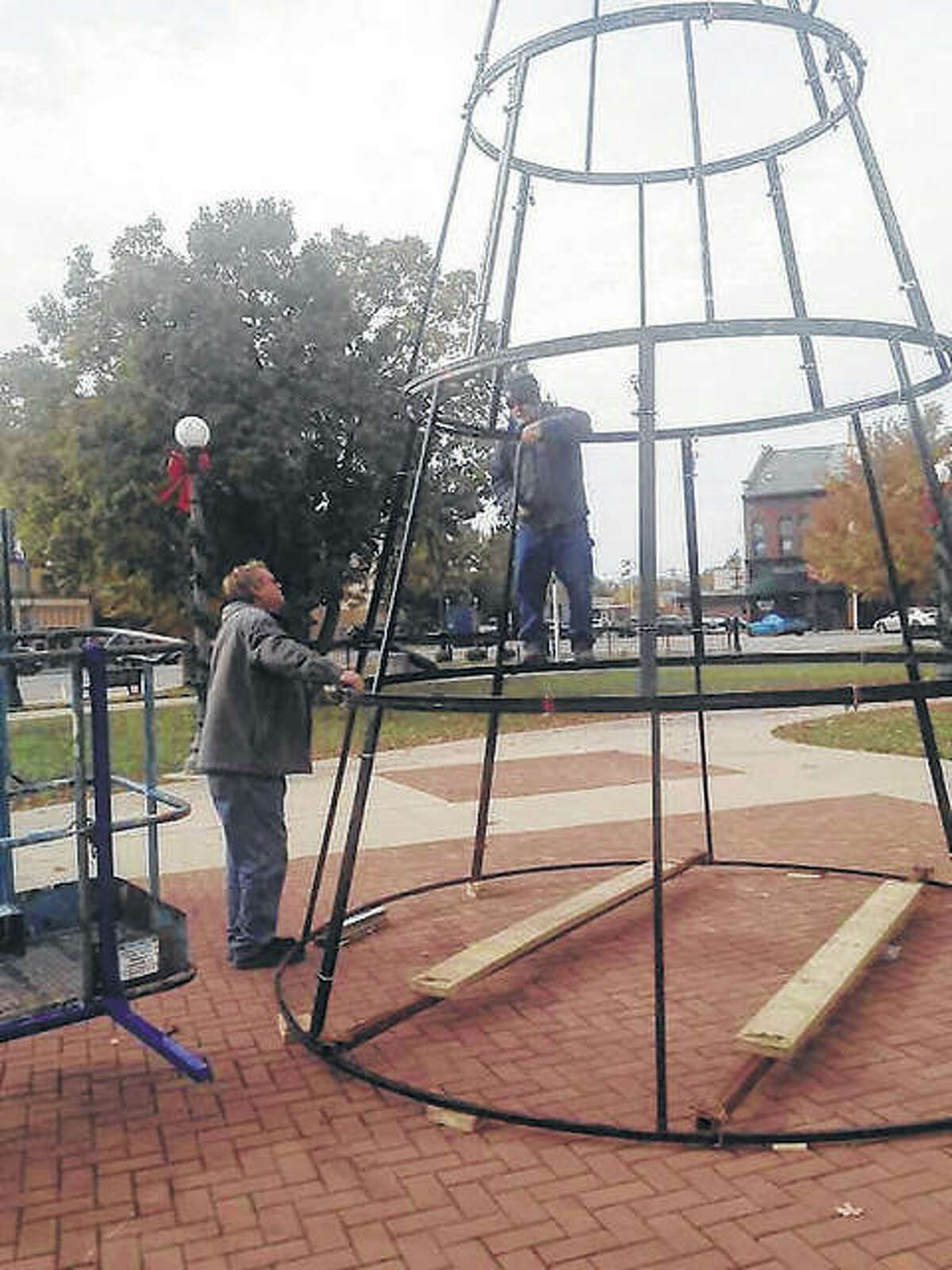 City employees Terry Chumley (left) and Terry Surratt work Tuesday on setting up the base for what will become the city’s Christmas tree in downtown’s Central Park. Crews will be working again today on getting the tree put together for the holiday season.