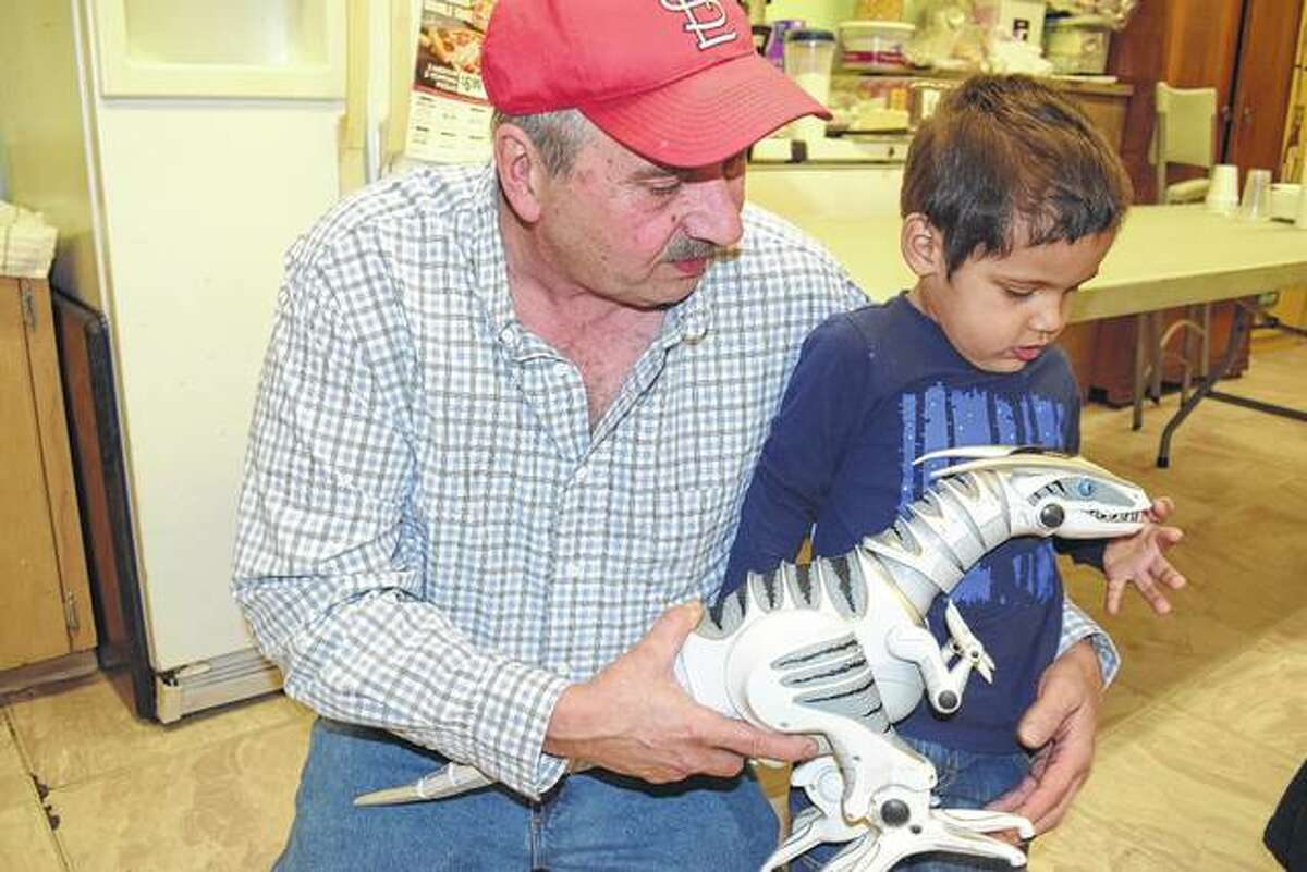 Dan Kosinski of South Jacksonville holds Andrew Israel after giving the boy a toy dinosaur at New Directions Warming and Cooling Center. Andrew is the son of Maurice Smith and Whitney Shipley.