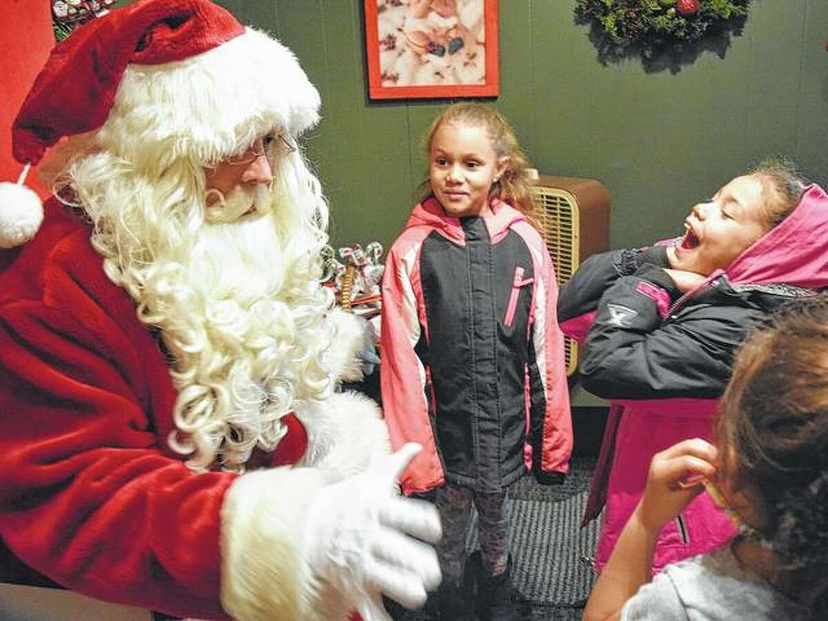 Santa Claus shares a laugh Thursday with Aleigha Suggs (from left), 4, the daughter of Allissa Suggs; Jayla Stout, 6, the daughter of Chelsea Stout; and Aeriana White, 7, the daughter of Allissa Suggs at his house on the square in Jacksonville.