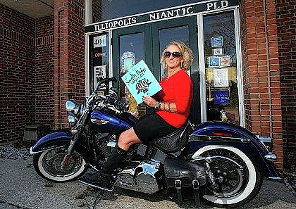 In this Dec. 5, 207 photo, librarian Shelley Hopkins poses with her Harley-Davidson motorcycle fondly dubbed "Rayce," outside the Illiopolis/Niantic Public Library with one of her favorite books in Illiopolis, Ill. Rayce (pronounced ray-see) is one of the reasons Hopkins, who celebrated her 25th anniversary as librarian on Dec. 4, said she is not a stereotypical librarian. "Librarians are quiet," Hopkins said. She jokingly says her voice and her laugh are loud, and that's part of what makes her different from the image people have of librarians, and then there's the bike and her tattoos. (Jim Bowling/Herald & Review via AP)