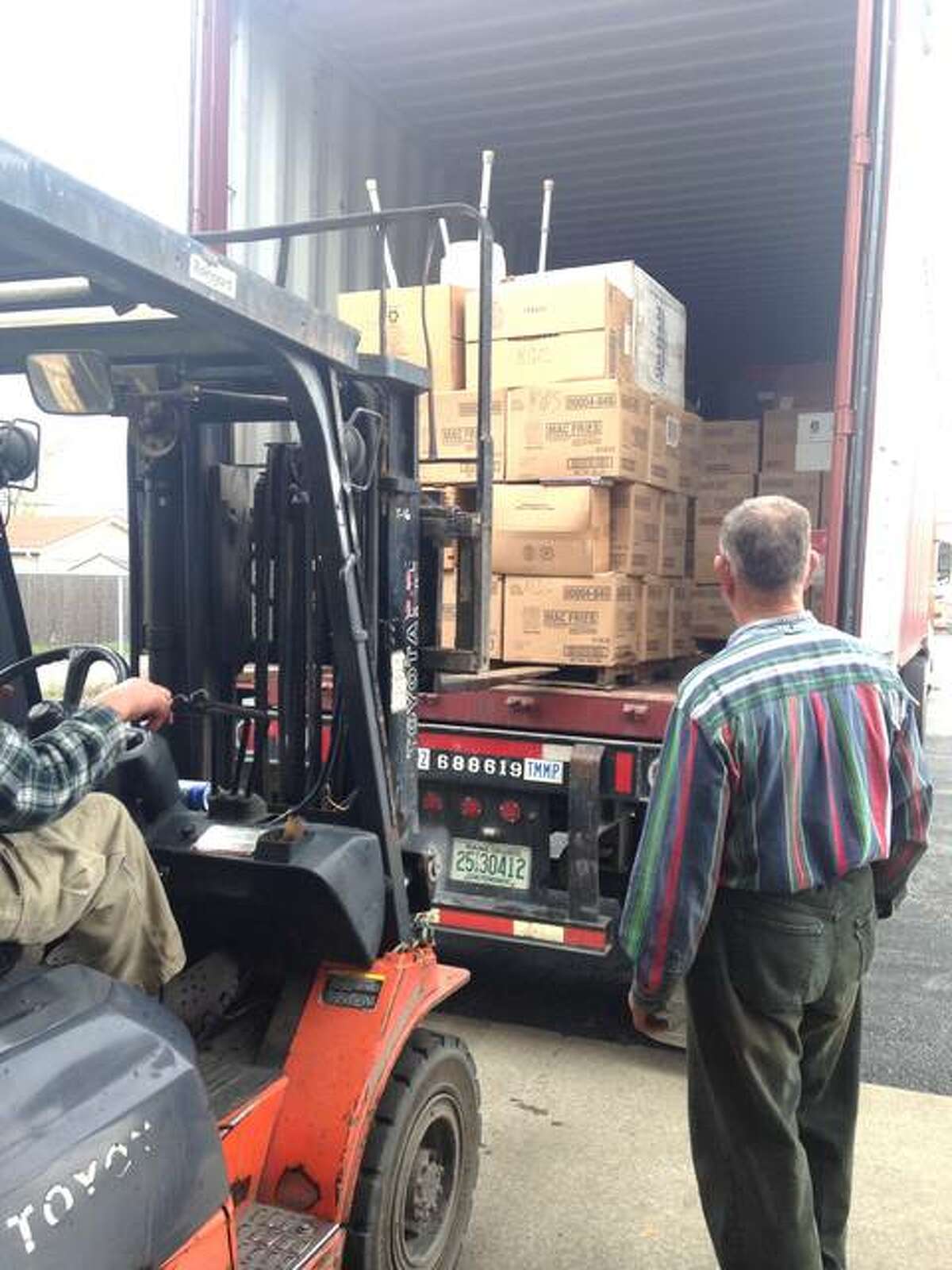Clifford Clark, right, of Alton, watches as an employee of Clark Boat and Supply loads another pallet of donated books into a cargo box headed for National Public Library of Antigua and Barbuda.