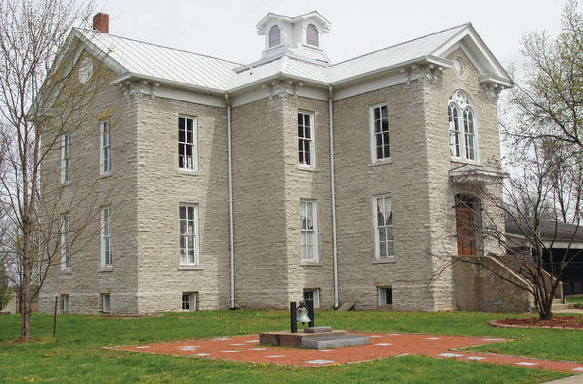 The exterior of Hamilton School with a bell monument in the foreground. The second floor was the designated church area. The inside of the school is in need of major repairs.
