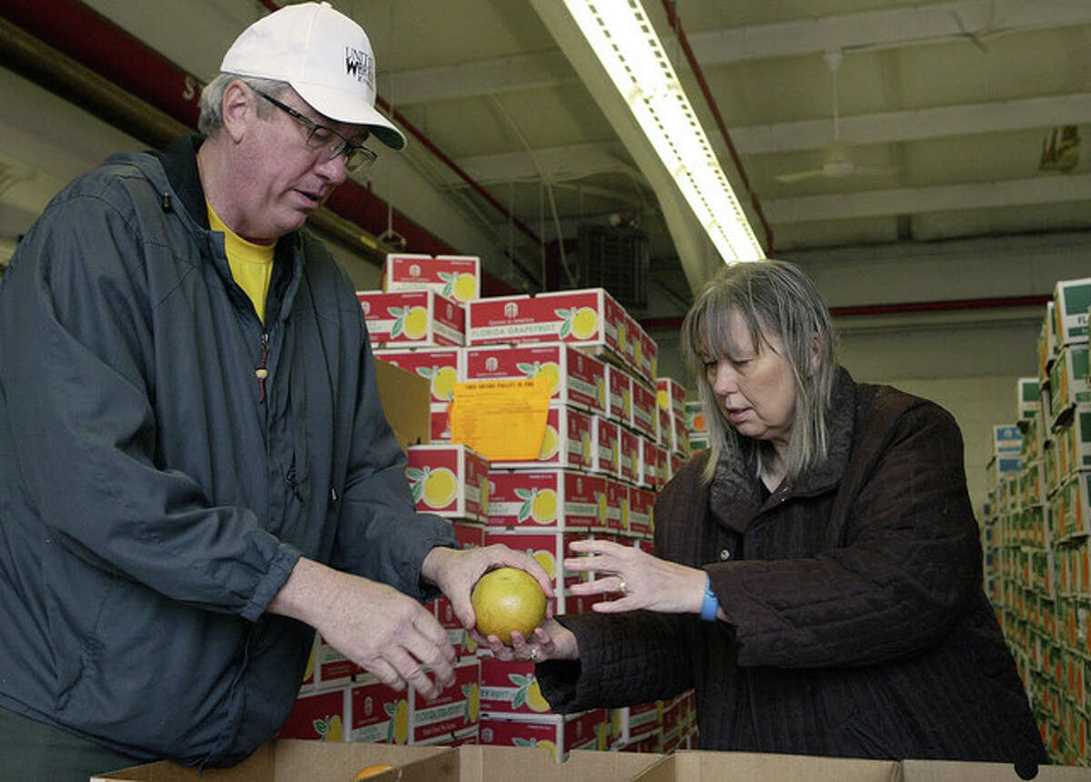 Lions Club member Tom Atkins (left) and Jana Atkins check for any bruises or bumps on fruit before sorting it for delivery.
