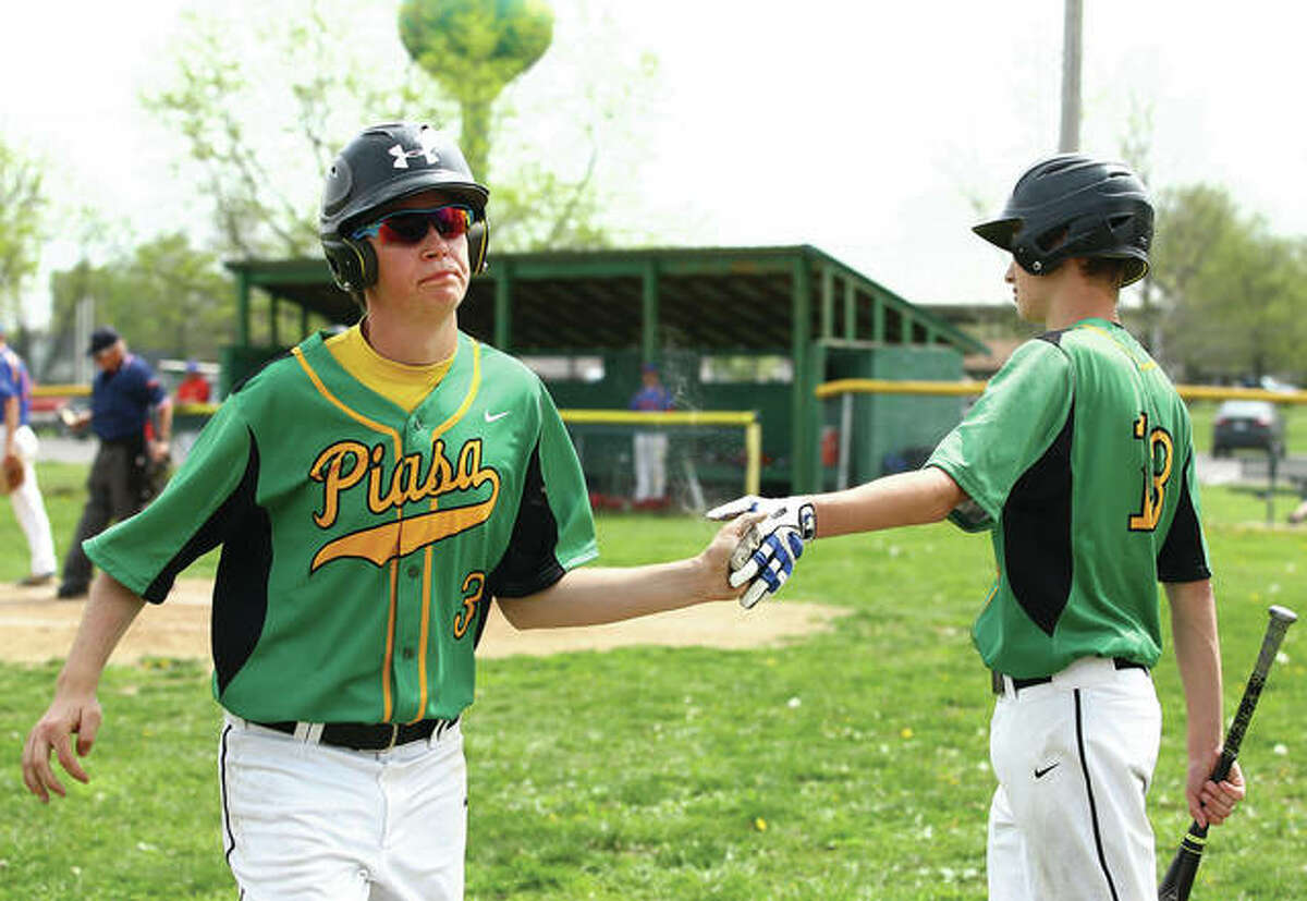 Southwestern’s Brock Seymour (left) is congratulated by Troy Evans after scoring a run in a SCC victory over Roxana on April 14 in Brighton. The Piasa Birds are 5-0 in SCC play and positioned to win a fifth consecutive conference title.