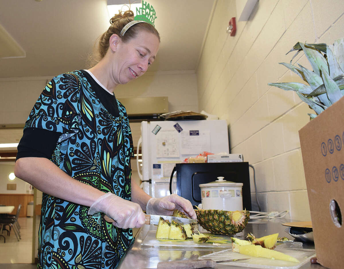 Kori Daniels, hostess for the Jacksonville Area Senior Center, slices pineapple Thursday in preparation for the center’s New Year’s party. Seniors were being treated to different foods and snacks at the afternoon bash.