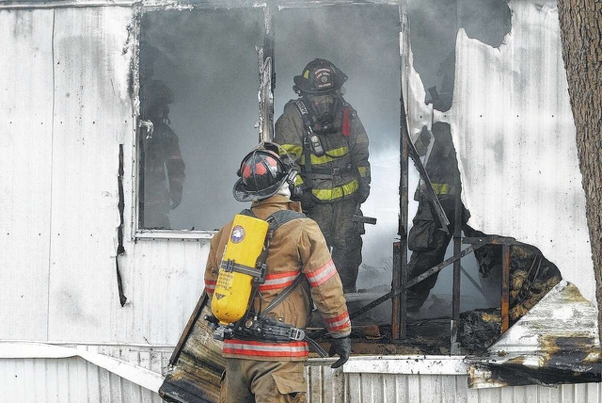 A South Jacksonville firefighter (foreground) and Jacksonville firefighter Brian Gillespie work Tuesday to extinguish a fire that destroyed a mobile home at 1033 E. Morton Ave., Lot 39. Jacksonville Fire Department Capt. Beth Kershaw said the fire is believed to have been caused by an electrical connection to a clothes dryer. Kershaw said no one was injured in the blaze.