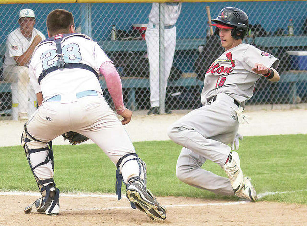 Alton’s Charlie Erler slides into home as Jersey catcher Collin Carey waits to make a tag.