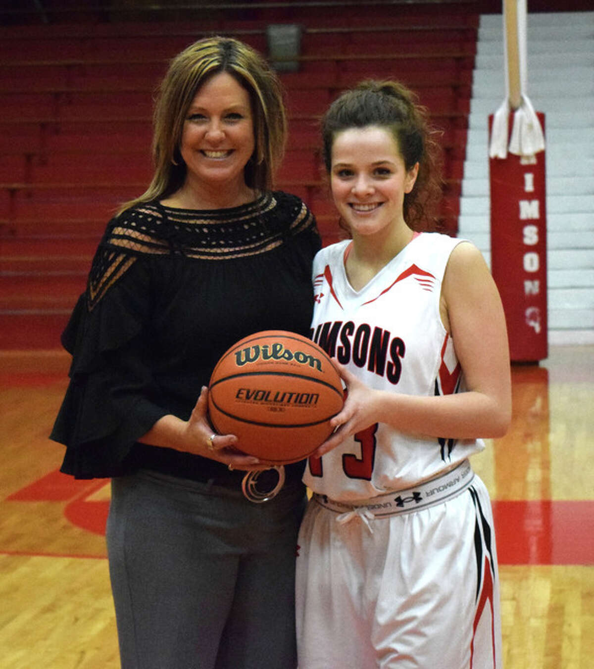 Jacksonville High’s Olivia Kaufmann poses with Jacksonville head coach Jeannette Barlow after Kaufmann scored the 2,000th point of her career in the Crimsons’ loss to Chatham Glenwood at the JHS Bowl Wednesday night.