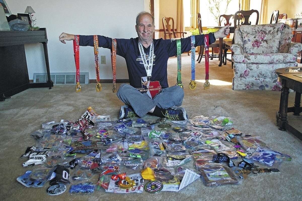 Jim Alexander of Jacksonville displays the memorabilia from the 100 marathons he has run in the past 10 years, including a Texas-sized medal from the Texas Marathon around his neck and six medals from Disney World, which was the location for marathon number 100.