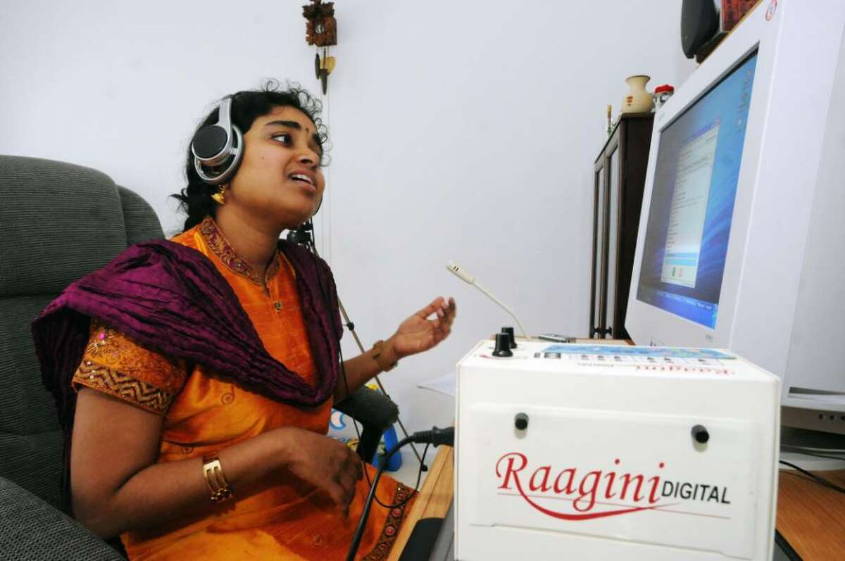 Indian musician and teacher, Vidya Subramanian, sings with an electronic tambura while doing a pod-cast on the computer at her home in Clifton Park, N.Y., in April of 2009. (James Goolsby/Times Union)