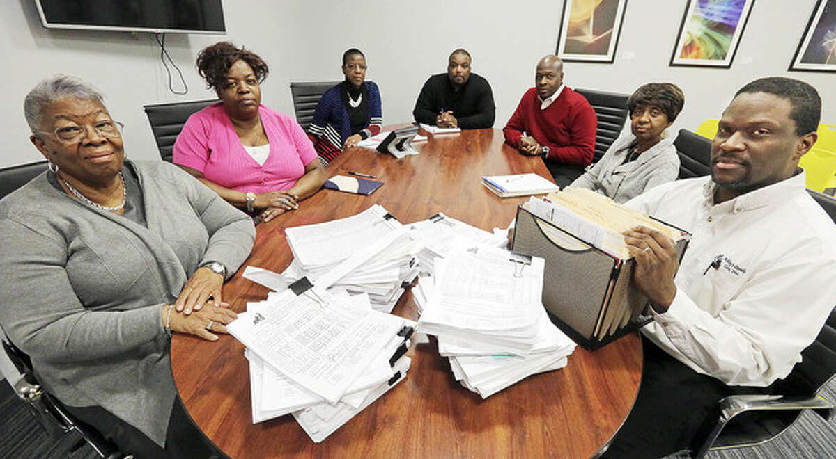 Frankie Redditt (left), president/CEO of Ashley’s Quality Care, and CFO Michael Robinson are joined by other officers at the company headquarters with stacks of invoices to the state and payroll bills on the table.