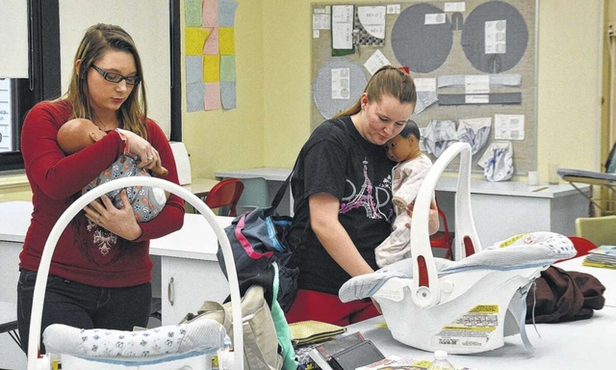 Pittsfield High School students Margaret Wright (left) and Lexus Ham tend to their “babies” as part of a parenting class.