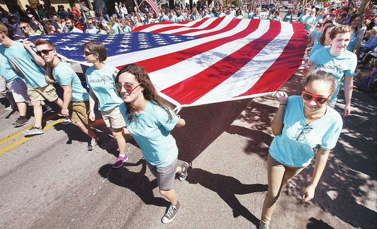 Members of the Christian musical group Encounter carry the large American flag up Washington Avenue in Alton Monday during the 150th annual Alton Memorial Day Parade. Thousands turned out under clear skies to watch the longest consecutive running Memorial Day parade in the nation.