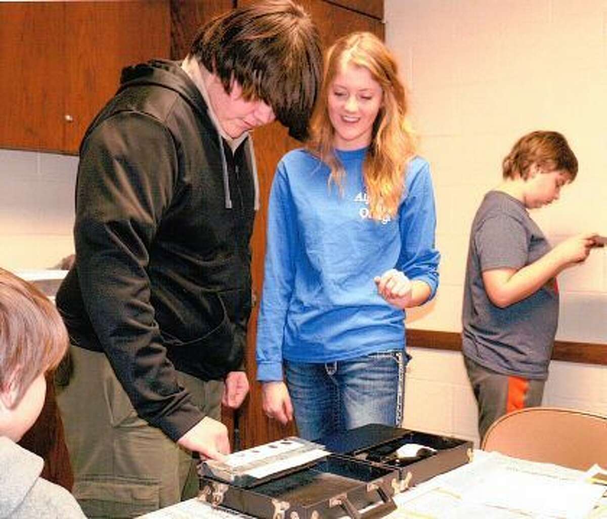 Ethan Elmore of Troop 107 takes his own fingerprints, guided by Madison Pfaff, a member of Illinois College’s Alpha Phi Omega, during a merit badge clinic.