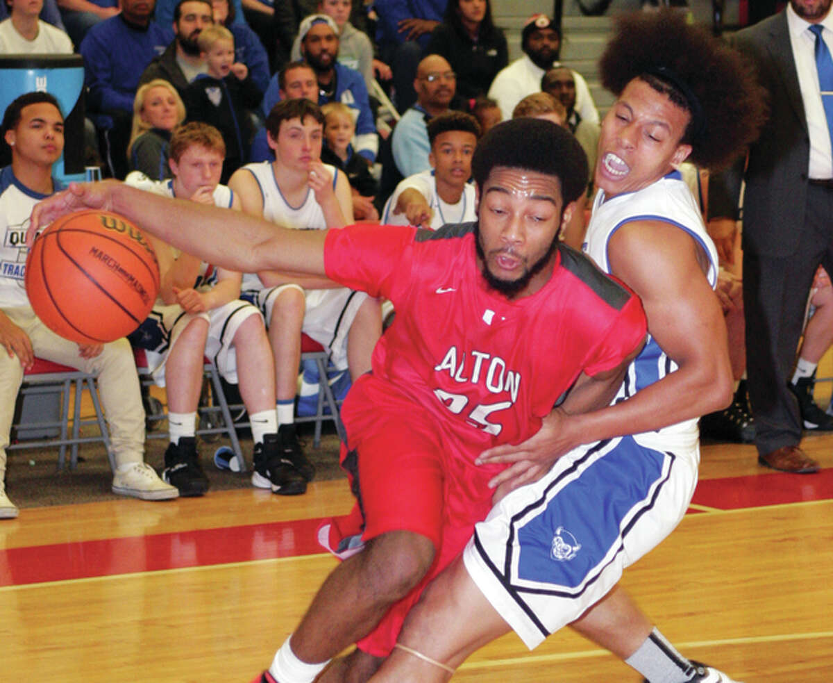 Alton’s Maurice Edwards (left) drives past Quincy’s Deven Smith and draws a foul during the championship game of the Alton Class 4A Regional on Friday night at Alton High in Godfrey.