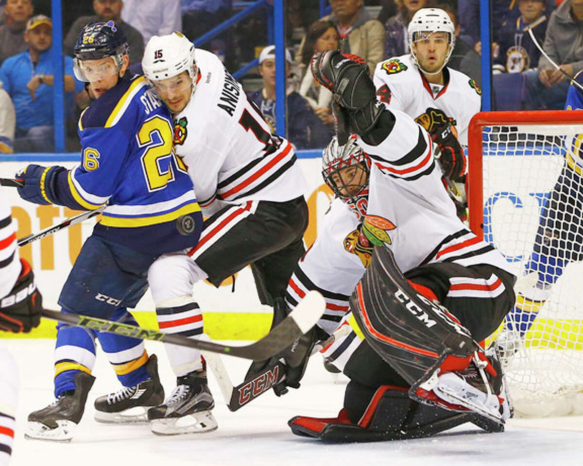 Chicago Blackhawks goalie Corey Crawford makes a save as teammate Artem Anisimov (15) and the Blues’ Paul Stastny (26) look for the rebound Wednesday night in St. Louis.