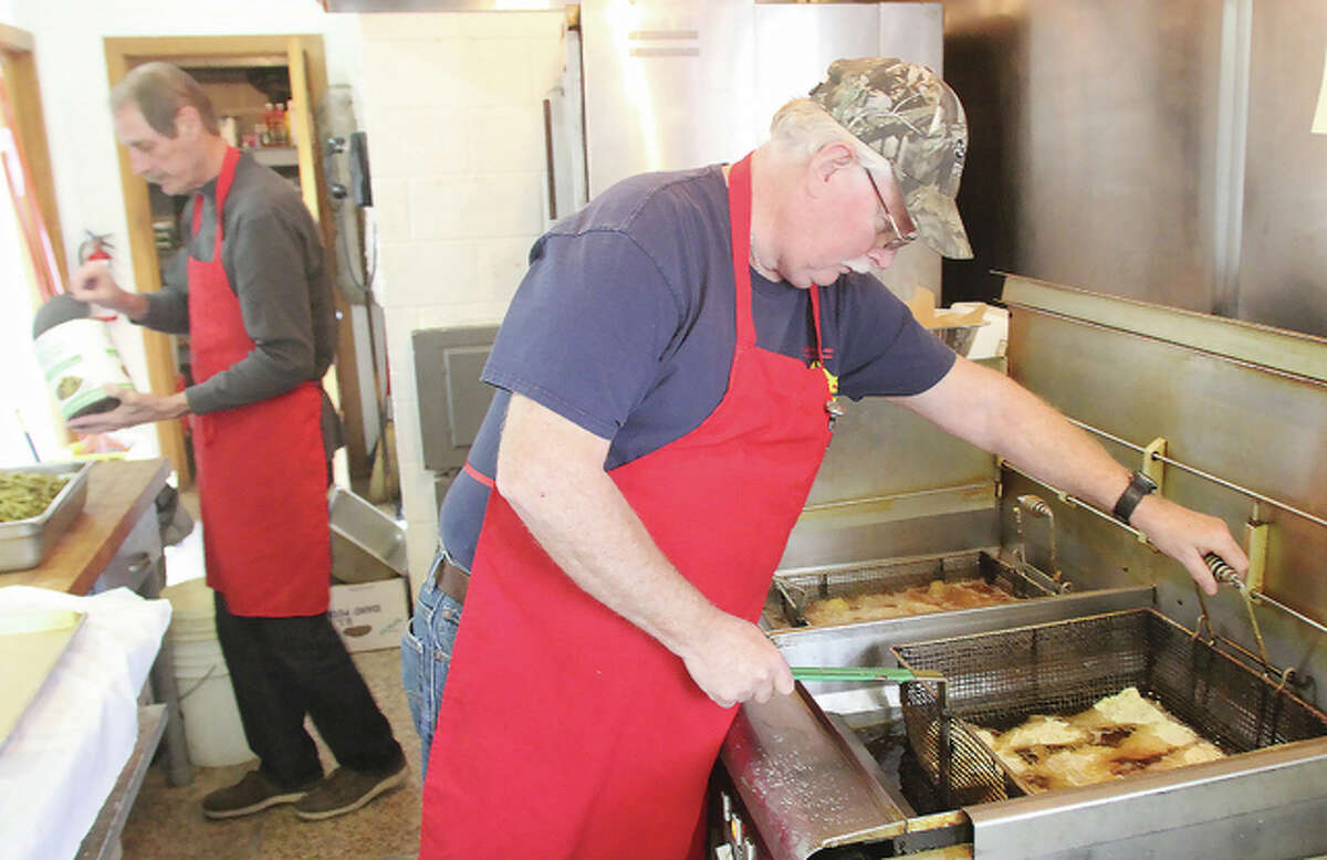 Steven Rynders, right, drops fish into a deep fryer at the Alton Knights of Columbus Friday afternoon as Joe Sasek works on a green bean/potato casserole. Cooks started working at about 2:30 p.m. in anticipation of their Good Friday fish fry, the last of seven Lenten fish fries this season.