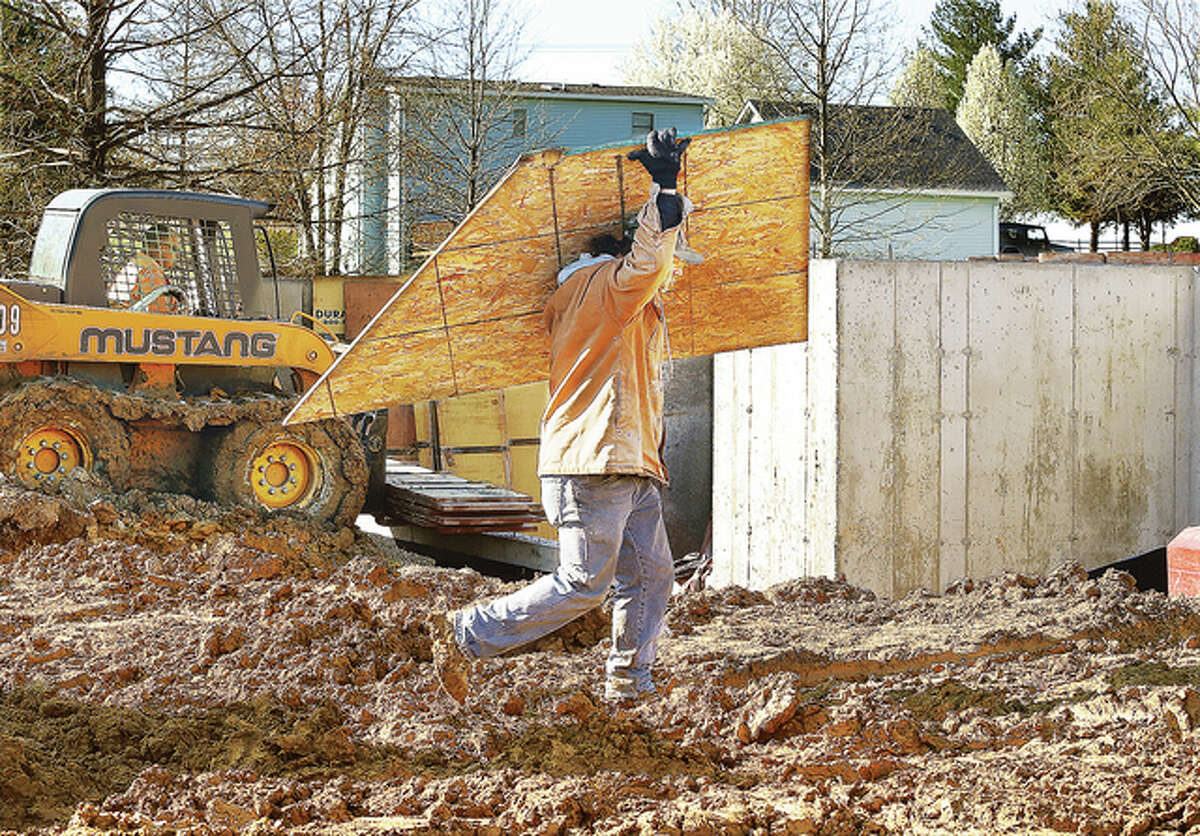 A worker carries a piece of wood to the foundation of a new house being built Friday by Homes by Emmons & Cress in Godfrey on Valleydale Road in the Eagle Pointe subdivision in Godfrey.