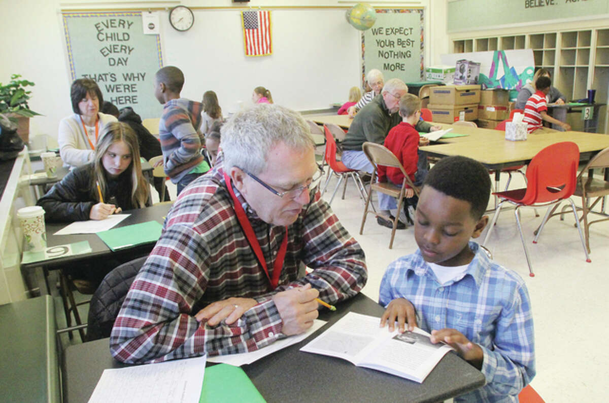 Volunteer Steve Forbes listens as Gilson Brown Elementary School second-grader Darence Edwards reads to him as part of the Reach Out and Read program in the Alton School District. All of the Alton School District’s elementary schools participate in the program, which pairs volunteers with children who read books to them.