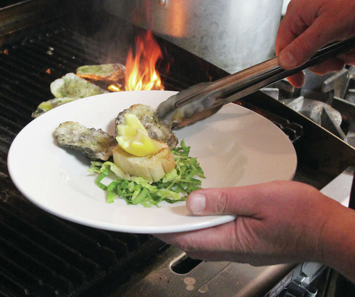 Scott Cousins/The Telegraph Brad Hagen, executive chef and partner/owner of the Grafton Oyster Bar, plates an order of char-grilled oysters at the restaurant this week. The restaurant opened March 1 and has "exceeded expectations" in the first month, according to Hagen.