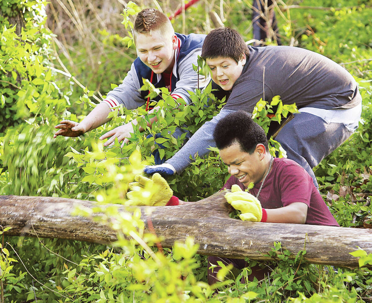 Alton Middle School students found out Friday that hard work can be fun. Three middle school boys work together to roll a log down the hillside on the west side of the school’s property during the AMS Service Day. A small army of students were clearing the hillside of bush honeysuckle and dead logs and branches.