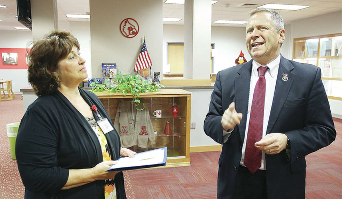 Brenda Powers, president of the Alton Education Association, left, listens in the library at Alton High School to U.S. Rep. Mike Bost, R-Murphysboro, talk during a visit to the school for Teacher and Staff Appreciation Week.