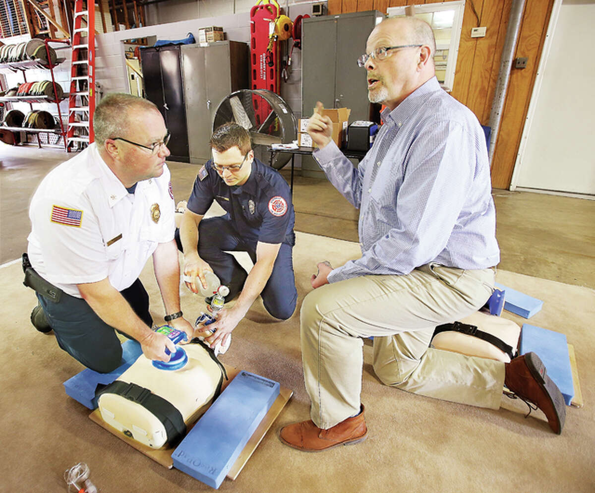 Mark Thurow, right, an EMT-paramedic and clinical educator for Zoll Medical Corp., talks to Godfrey firefighters about the use of their new ResQCPR system, being practiced, left. The Godfrey Fire Protection District is the first fire department in the state to start using the new system, which improves the efficiency of CPR. The system is made up of two parts, the ResQPUMP which attaches to the victim’s chest, left, and allows a lifting force in addition to the traditional downward pressure of CPR. The other component, the ResQPOD, center, which is attached to the ventilator, prevents the influx of unnecessary air through the patient’s airway. When the U.S. Food and Drug Administration-approved devices are used together, they improve the likelihood of one-year survival after cardiac arrest by 49 percent.
