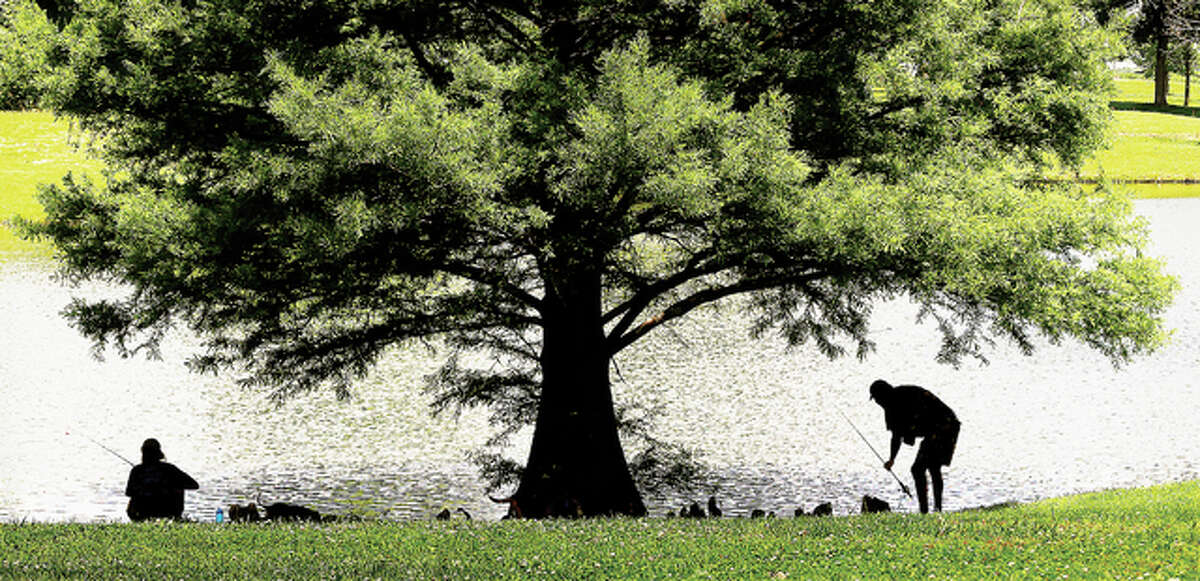 Two men take advantage of the shade from a tree next to the lake at Wood River’s Belk Park Tuesday for a little fishing. Work on a $400,000 project that includes walking trails at Belk Park and a restroom/concession stand at the soccer park on Rock Hill Road is expected to start in about two weeks.