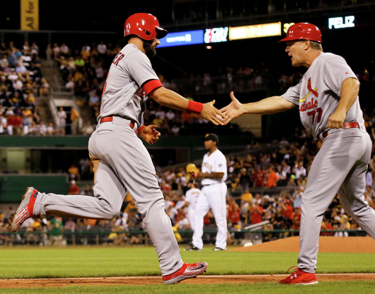The Cardinals’ Matt Carpenter (left) is greeted by third base coach Chris Maloney after hitting a three-run home run during the eighth inning Friday night in Pittsburgh.