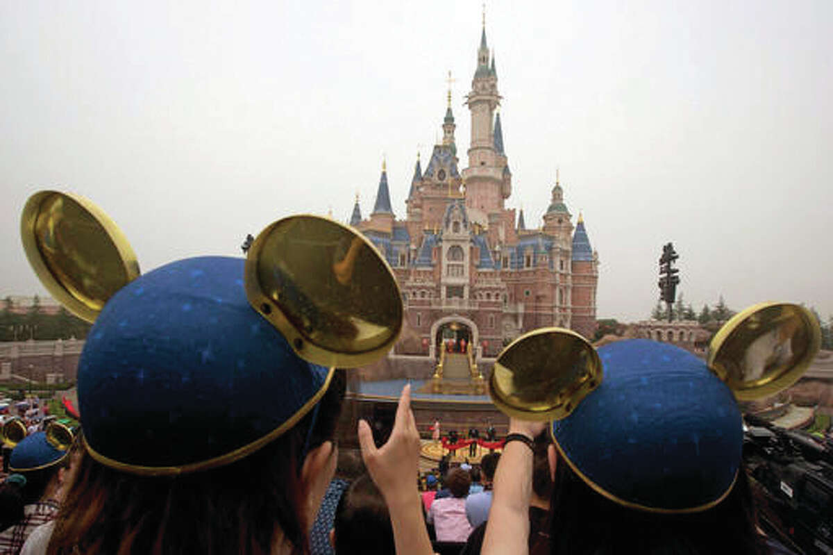 Visitors wearing Mickey hats take photos of Shanghai Mayor Han Zheng, left, Chinese Vice Premier Wang Yang, center, and Disney CEO Bob Iger preparing to cut the red ribbon during the opening ceremony for the Disney Resort in Shanghai, China, Thursday, June 16, 2016. Walt Disney Co. opened its first theme park in mainland China on Thursday at a ceremony that mixed speeches by Communist Party officials, a Chinese children’s choir and actors dressed as Sleeping Beauty and other Disney characters. (AP Photo/Ng Han Guan)