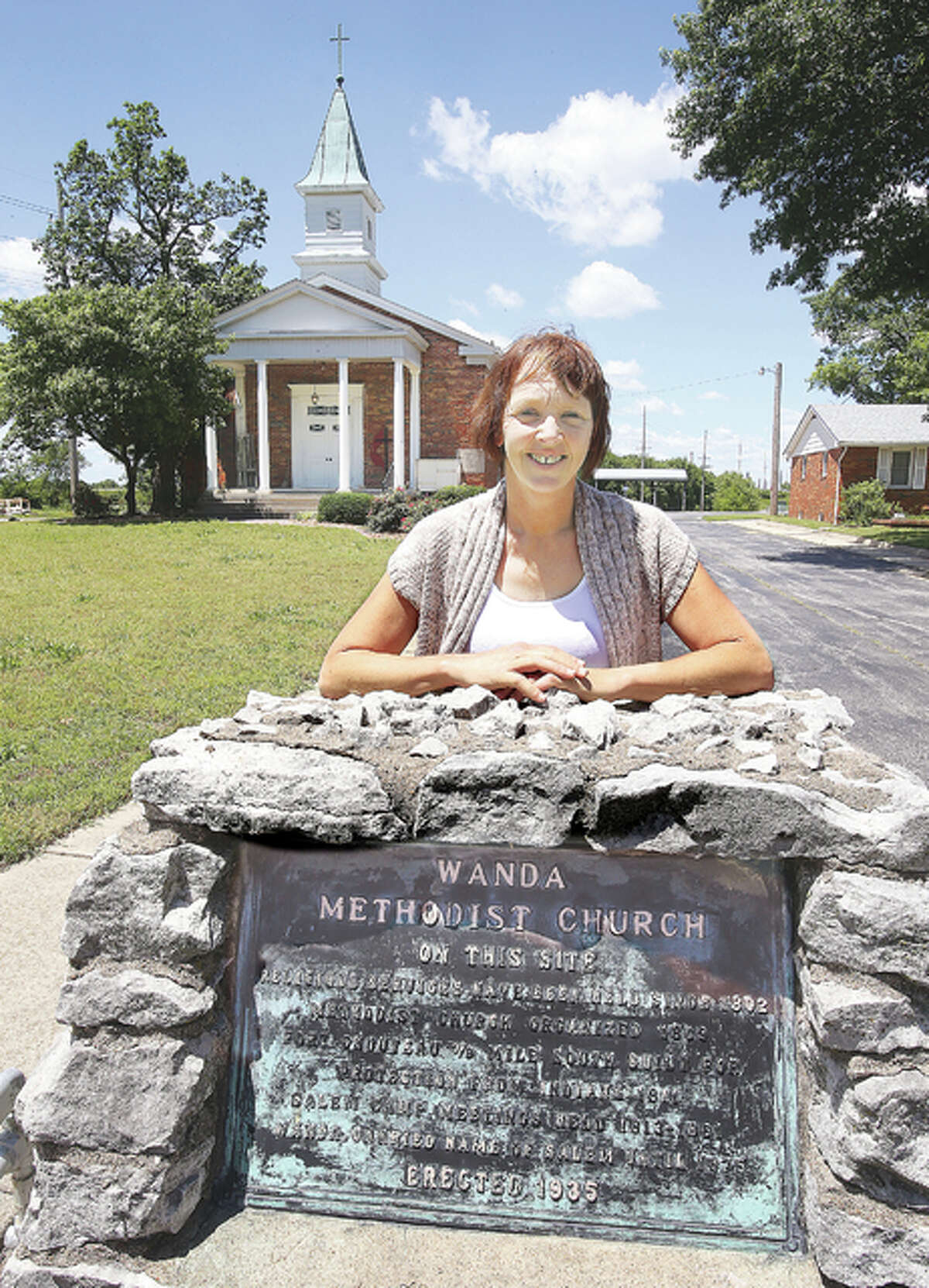 Administrative Assistant Shelly Dalton at the historic Wanda United Methodist Church located in an area known as “Wanda,” tucked away on Old Edwardsville Road, between South Roxana and Edwardsville, stands by the marker that states the church has had a church building on the same site since 1802. The current church, background, was built in 1957, but a church has stood on the same spot for more than 200 years.